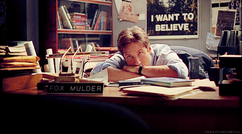 "Fox Mulder from The X Files burying his head in his arms on his desk"
